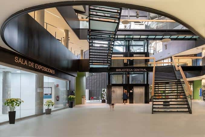 Interior del hall principal con escaleras y señalización de Sala de Exposiciones