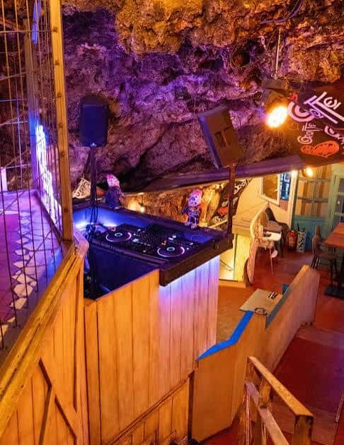 Escenario con equipo de DJ y luces de colores en la cueva