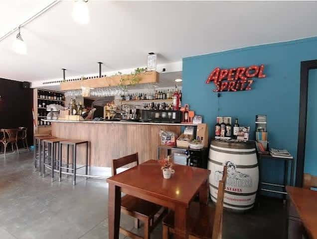 Interior del bar con mostrador de madera y estanterías de vinos
