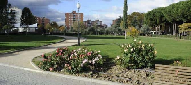 Paisaje del parque con senderos curvos, rosales en flor y zonas verdes amplias