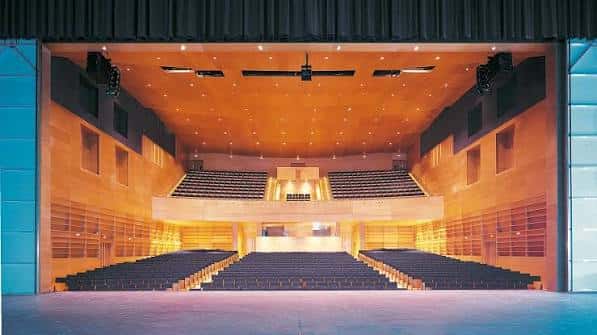 Interior del auditorio principal con butacas azules y techo de madera