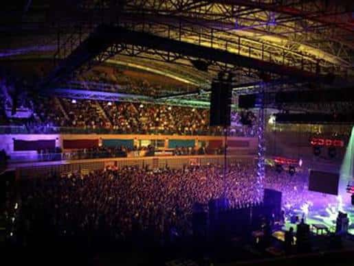 Interior del pabellón durante un evento con escenario iluminado y multitud de asistentes