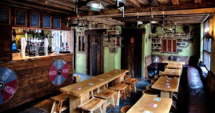 Vista del área del bar con mostrador de madera y decoración de escudos nórdicos