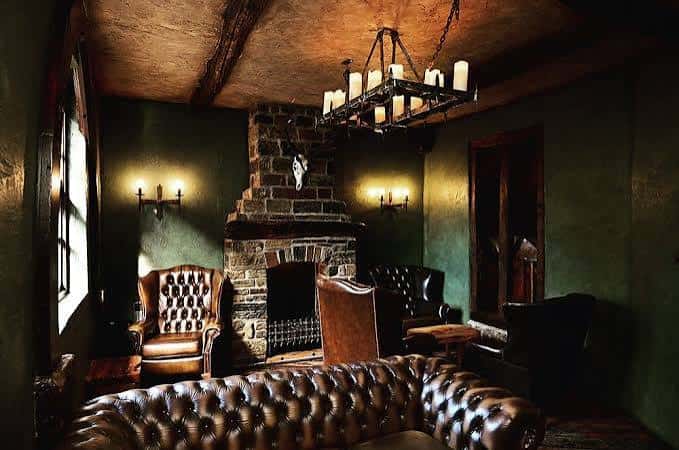 Sala de estar acogedora con chimenea de piedra y sofás de cuero Chesterfield