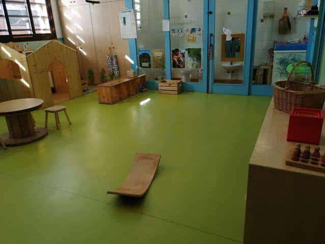 Aula interior con suelo verde y mobiliario de madera