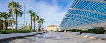 Recorrido del paseo marítimo con la estructura de sombra moderna y edificios costeros al fondo