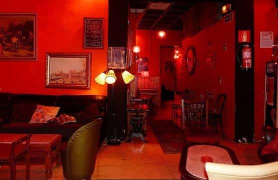 Interior acogedor del Rouge Cocktail Club con paredes rojas y mobiliario clásico
