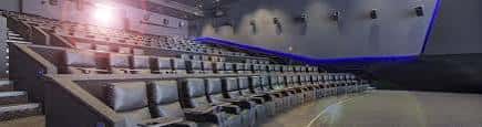 Interior de una sala de cine con butacas de cuero y luces azules