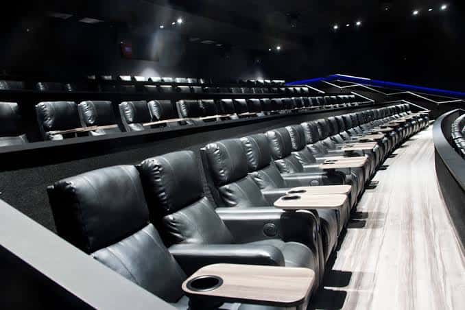 Sala de cine con butacas de cuero y mesas laterales