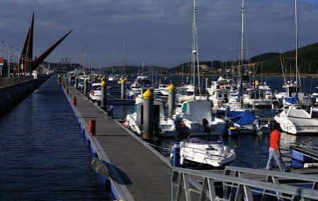 Muelle del puerto deportivo con yates y barcos bajo cielo nublado