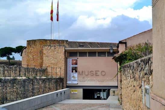 Vista exterior del Museo de Segovia con fachada de piedra y bandera