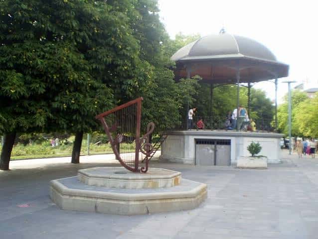 Kiosco de música y escultura de arpa en el Paseo de la Condesa de Sagasta, con personas disfrutando del espacio público