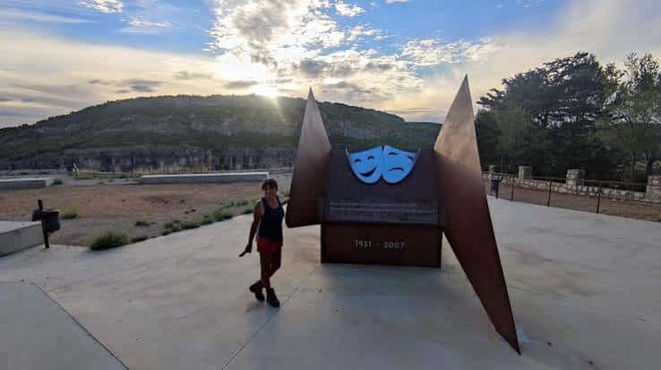 Vista del homenaje al atardecer con silueta de la escultura y cielo dramático