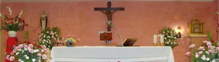 Altar de la Parroquia de San Juan de Dios con flores y crucifijo
