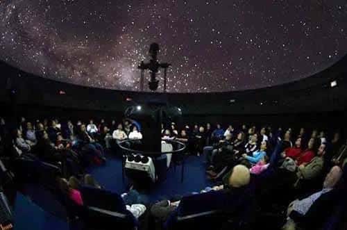 Interior del planetario durante una proyección estelar con público sentado