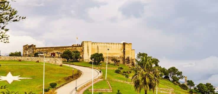 Castillo Sohail desde el parque con senderos y palmeras