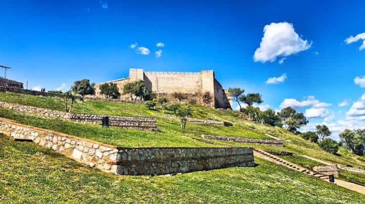 Vista panorámica del castillo sobre colina verde con cielo azul