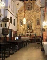 Interior de la iglesia conventual con retablo dorado y bancos de madera
