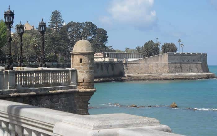 Fortaleza histórica junto al mar con farolas ornamentales en primer plano