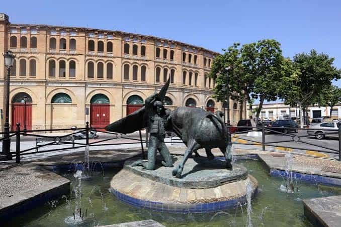 Vista exterior de la Plaza de Toros con la estatua del torero y el toro en primer plano