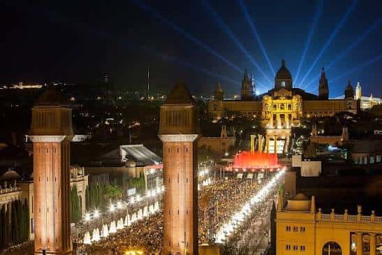 Escenario nocturno festivo con iluminación láser y luces decorativas en la avenida, ideal para eventos celebrativos