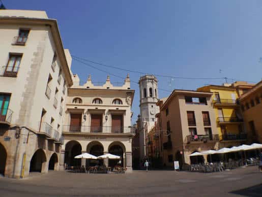 Plaza de la Vila con edificios coloniales y campanario al fondo, ideal para eventos al aire libre