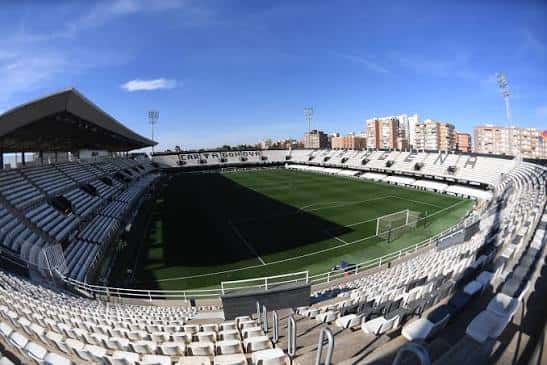 Vista panorámica del interior del Estadio Cartagonova con gradas vacías y campo de césped bajo cielo azul