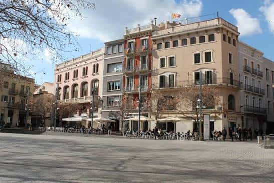 Vista panorámica de la Plaça Vella con edificios históricos y terrazas al aire libre