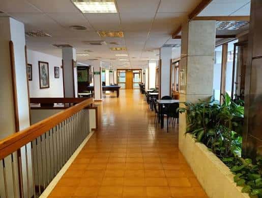 Pasillo interior con suelo de baldosas, plantas y mesas para eventos