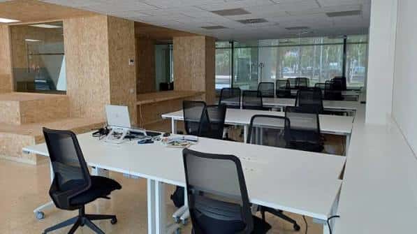 Interior del Espai de Cotreball Lluís Serra con mesas de trabajo y sillas