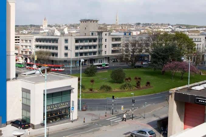 Vista elevada del entorno de Derrys Cross mostrando el edificio principal, la rotonda y la ciudad de Plymouth al fondo