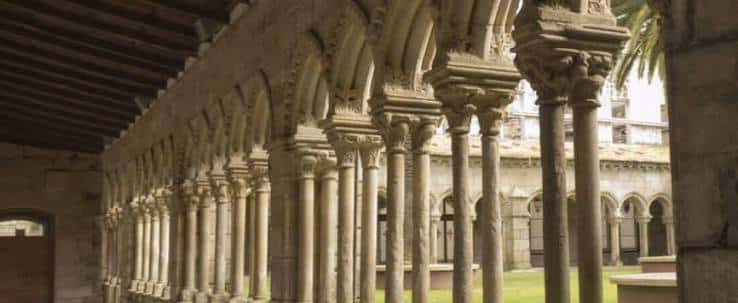 Claustro románico con arcos y columnas de piedra bajo techo de madera