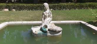 Fuente con estatua de sirena en el parque Joan Oró, rodeada de césped y setos