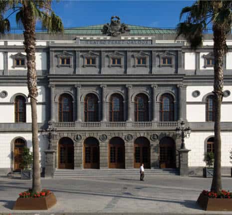 Vista frontal del teatro con entrada principal y dos palmeras a los lados