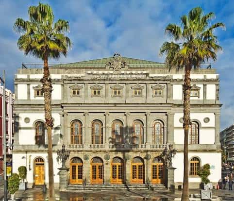 Fachada del Teatro Pérez Galdós con cielo azul y palmeras en primer plano