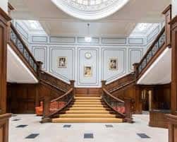 Gran escalera de madera con barandillas ornamentales y techo abovedado en el interior del centro