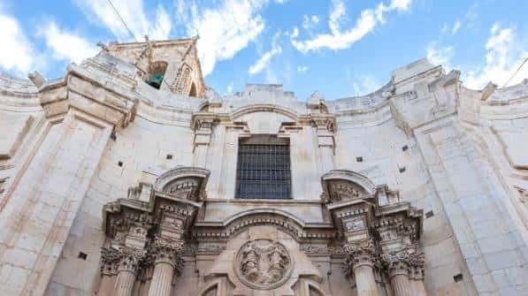 Vista frontal de la fachada de la iglesia con cielo nublado de fondo