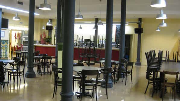 Interior del espacio con mesas y sillas apiladas, ideal para eventos