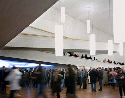 Patio interior del teatro con iluminación moderna y público en movimiento