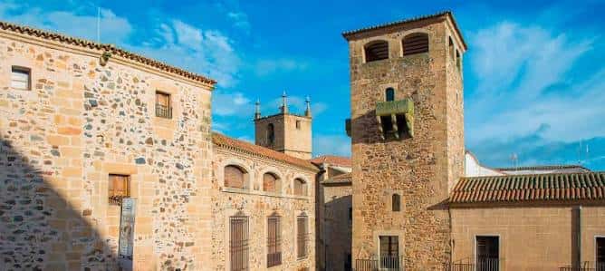 Vista panorámica del Palacio de los Golfines de Abajo con su torre y fachada de piedra bajo un cielo azul