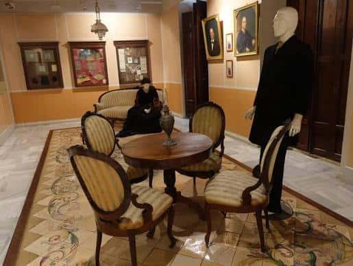 Sala de exposiciones con mobiliario antiguo y maniquíes vestidos con trajes históricos