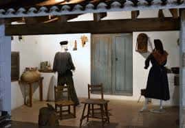 Escena etnográfica con maniquíes y objetos tradicionales en un espacio interior