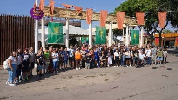 Grupo de visitantes posando frente al acceso del campamento festero