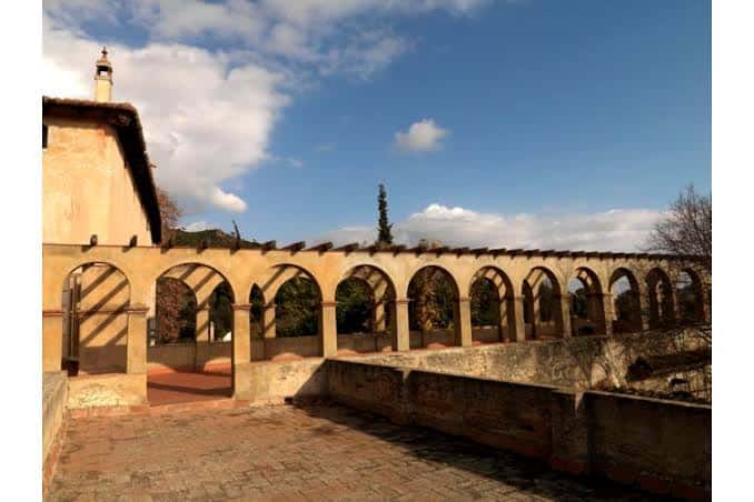 Pórtico con arcos de la Masía de Can Miravitges bajo un cielo azul