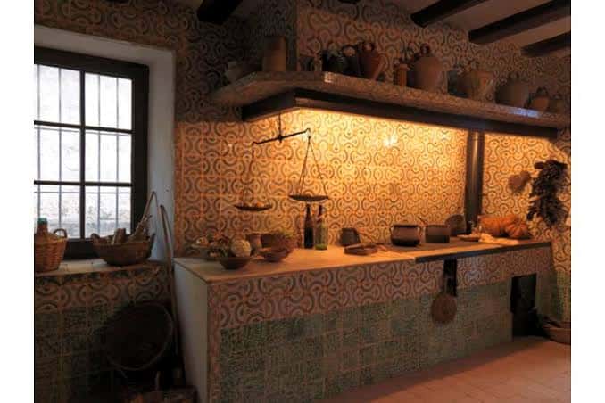 Cocina tradicional de la Masía de Can Miravitges con azulejos decorativos y utensilios antiguos
