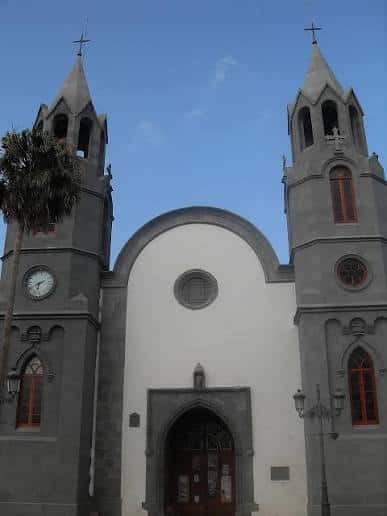 Vista frontal de la Iglesia de La Majadilla con sus dos torres y reloj bajo un cielo azul