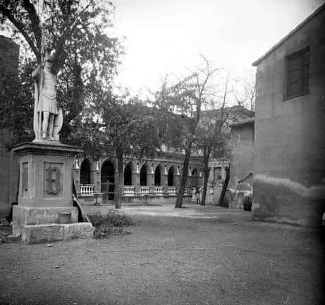 Vista histórica en blanco y negro del patio central con columnas y una estatua