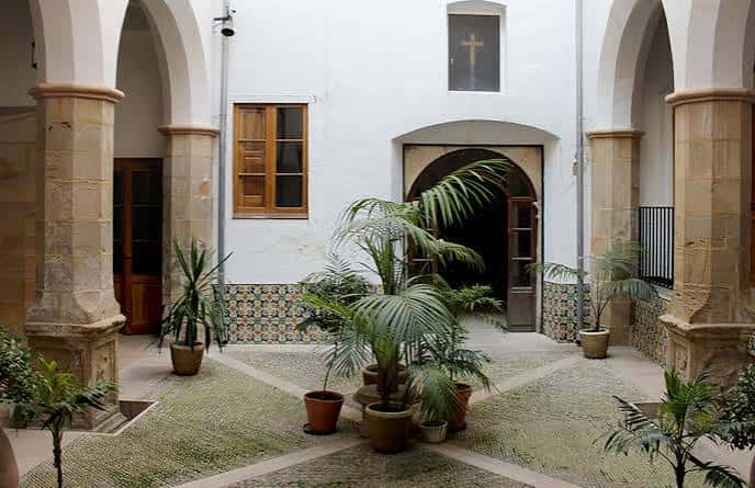 Patio interior del convento con arcos de piedra y plantas decorativas