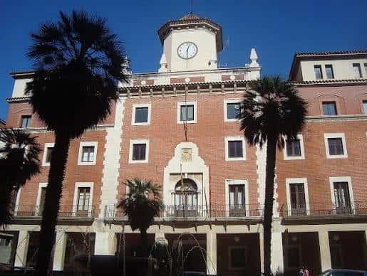 Fachada principal del edificio con palmeras y cielo azul