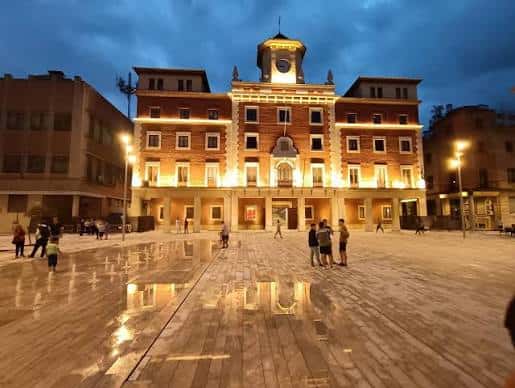 Vista nocturna del Ayuntamiento iluminado en la plaza